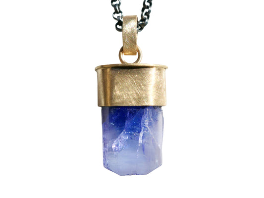 Raw uncut purple-blue tanzanite pendant set in 14k yellow gold with black sterling silver chain