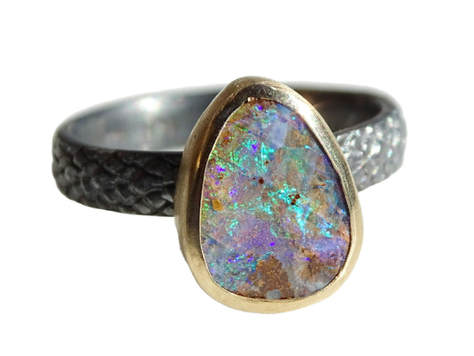 Black sterling silver opal ring with Australian boulder opal set in 14k gold bezel, featuring vibrant color play and textured band