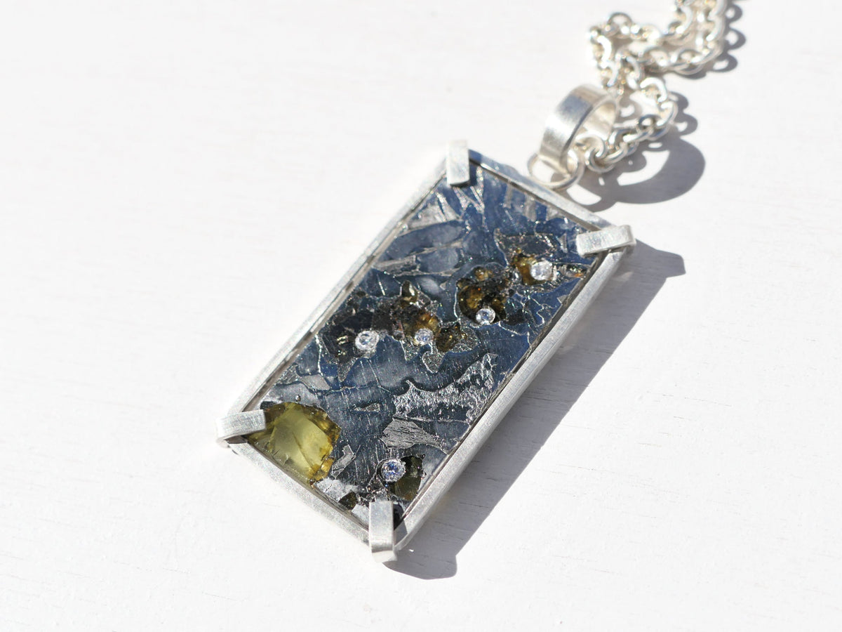 Large Pallasite Meteorite Pendant in sterling silver, featuring a rectangular dark metallic meteorite with olive crystals and diamond accents.