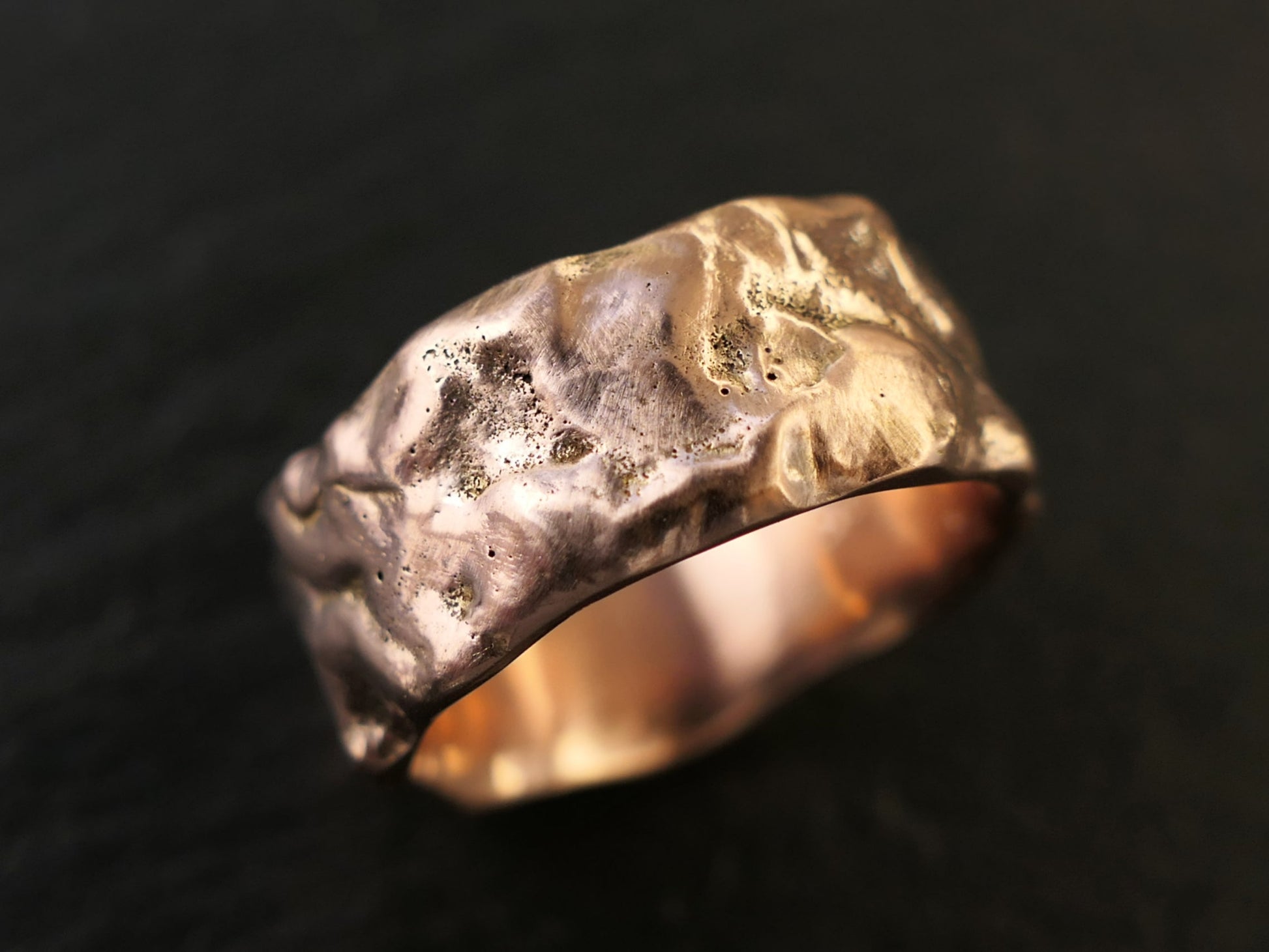 molten gold wedding ring on black background