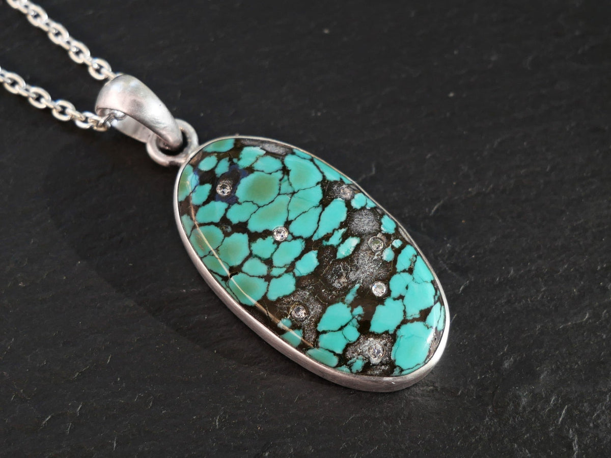 Genuine Turquoise Pendant necklace with vivid blue-green nodules in a black matrix, sterling silver bezel and diamond accents.