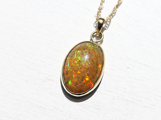 Big honeycomb welo opal pendant in 18k gold with vibrant multicolor pattern and solid gold setting