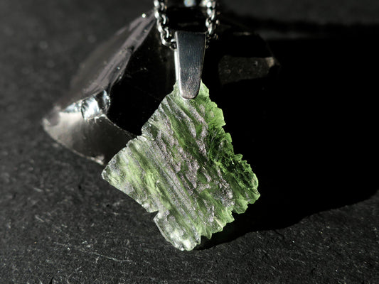 Raw Moldavite crystal pendant with black sterling silver bail on chain.